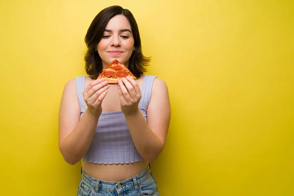 ゴージャス若いです女性保持し 黄色の背景にペパロニピザのスライスを見て — ストック写真