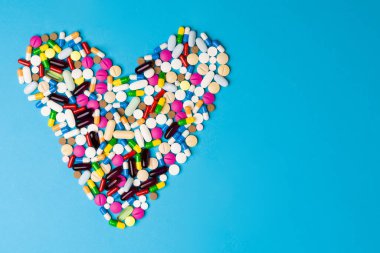 Sağlığınızı koruyun. Reçeteli haplar, ilaç antibiyotikleri, vitaminler ve renkli haplar metin için kopyalama alanı olan bir aşk kalbi oluşturuyor.