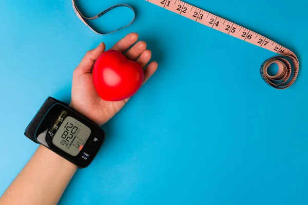 体重減少と栄養 健康的な女性は テープメジャーの横に彼女の手に心臓を保持しながら 彼女の血圧を取ります — ストック写真