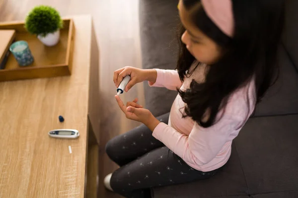 自宅で血糖値をテストするためにデジタルモニターを使用して糖尿病の病気の子供のトップビュー — ストック写真