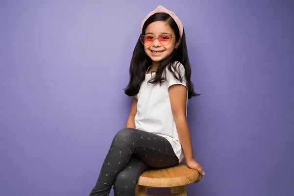 Menina Atrevida Sentado Banquinho Enquanto Vestindo Óculos Sol Coração Moda — Fotografia de Stock