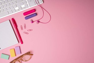 Pembe çalışma alanı. Kulaklıkları, gözlükleri, not defterleri, kalemleri ve kalemleri fotokopi alanının yanında. 