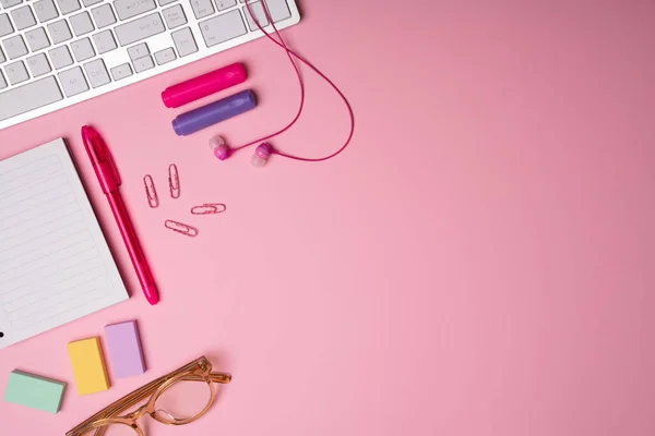 ピンクのワークスペース スペースをコピーする横に彼女のイヤフォン メモ帳 ペンとマーカーと女性のオフィスデスクのフラットレイアウト — ストック写真