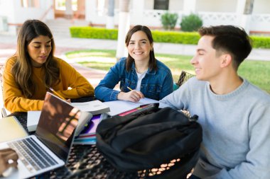 Cheerful female student feeling happy to study and do homework with her smart college friends at university