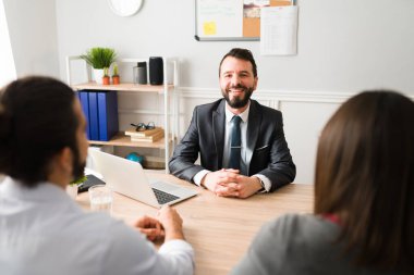 Cheerful financial advisor with a couple at the office. Portrait of an hispanic lawyer or accountant with clients 
