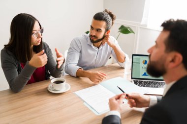 Application document. Advisor providing financial services to a young couple in his office