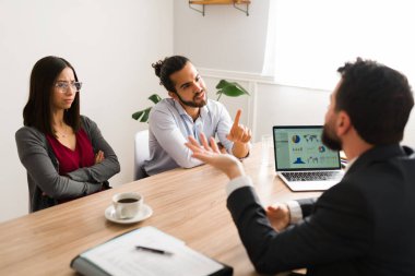 Wait a moment. Angry young couple arguing with a lawyer about their legal problems