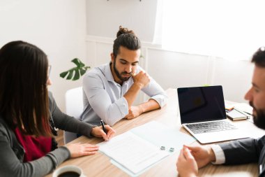 Upset young man and his ex wife signing a divorce settlement. Sad couple divorcing with a lawyer 