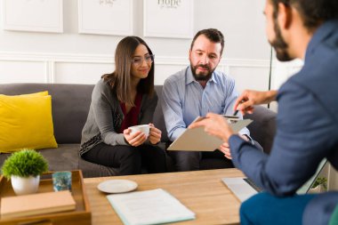Making a business deal. Attractive couple signing an agreement contract with a financial advisor at their home 