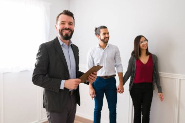 Yakışıklı bir emlakçının portresi yeni evi gezdirirken ve gülümseyen bir çifte evi gezdirirken mutlu oluyor.