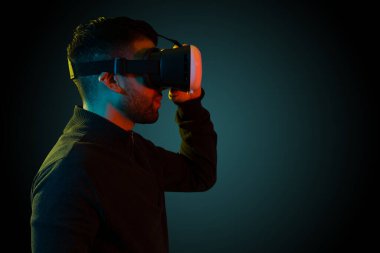 Side view of an attractive man adjusting his VR headset. Hispanic man testing future immersive technology 