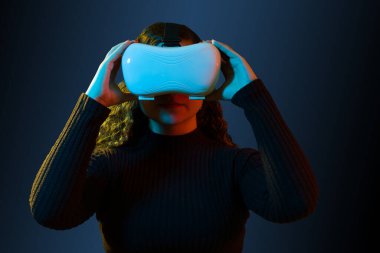 Beautiful woman using technology of the future. Woman adjusting her virtual reality headset against a modern background