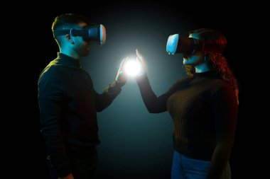Profile of a young woman and man touching a digital light and experiencing a simulation with virtual reality glasses clipart