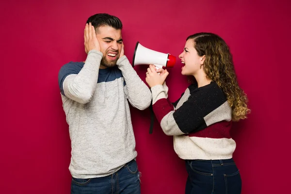 Listen to me! Angry young woman screaming with a megaphone to his upset boyfriend and having communication problems