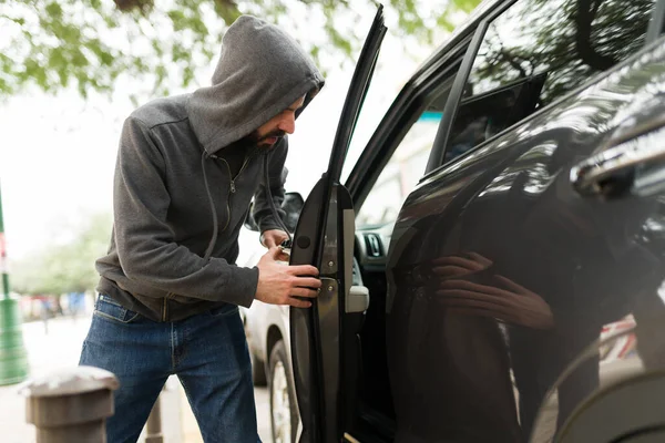 危险的汽车窃贼在光天化日之下偷车 罪犯闯入街上的一辆汽车 — 图库照片