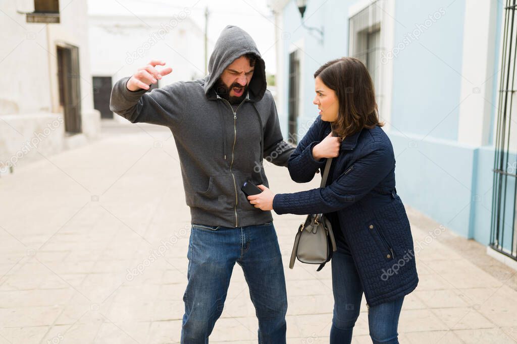 Angry woman victim using a stun gun for self-defense to prevent an assault or robbery while alone on the street