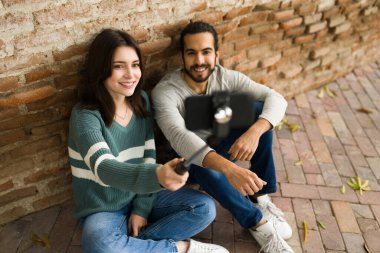 Sosyal medyada paylaşım yapmak için parkta selfie çubuğu kullanan çekici bir çift.