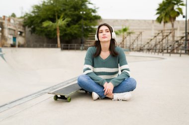 Paten parkında dinlenme günü. Kablosuz kulaklıkla müzik dinleyen muhteşem bir kadın. 