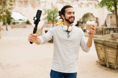 Şehirdeki en iyi kahve. Neşeli İspanyol adam, sosyal medyası için video kaydederken kahkaha atıyor ve kahve içiyor. 
