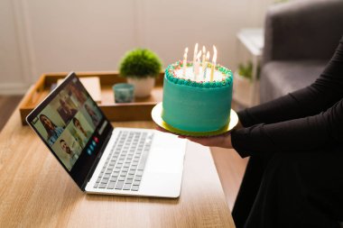 Doğum günümü tek başıma kutluyorum. Arkadaşları çevrimiçi bir videoda doğum günü şarkısını söylerken pastalı bir genç. 