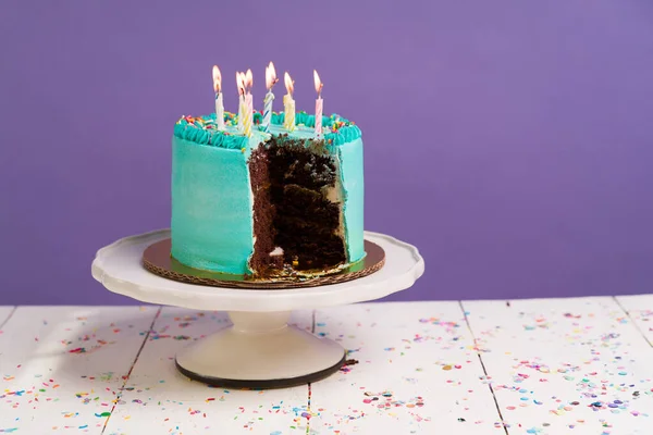 Lit birthday candles. Beautiful chocolate cake on a table for a birthday party celebration with a purple background