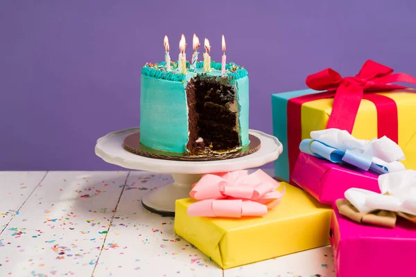 巧克力蛋糕 配上美味的蓝色糖霜和点燃的蜡烛 并配上漂亮的礼物 参加派对庆祝活动 — 图库照片