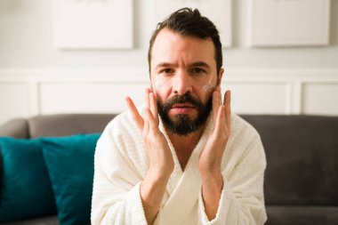 Sağlıklı cilt. Parlak ciltli genç adam günlük cilt bakımını yapıyor ve nemlendirici krem sürüyor.