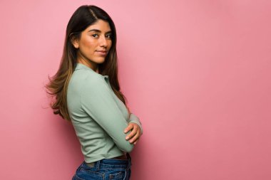 Kollarını kavuşturup fotokopi alanının yanında göz teması kuran gizemli genç bir kadının profili.