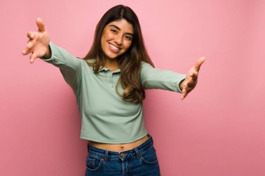 20 'li yaşlarındaki sevimli bir kadın kolları açık ve sarılmaya ya da kucaklaşmaya hazır.