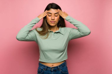 Hasta latin kadın şakaklarını ovuyor ve şiddetli bir baş ağrısı ya da kötü bir migren hissediyor.