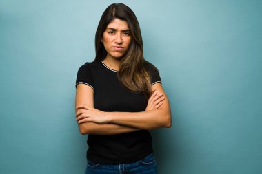 Tahammül edemiyorum. Üzgün İspanyol kadın kameraya bakarken kolları çaprazlanmış kızgın bakıyor.