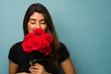Çiçekleri severim. Çekici bir genç kadın romantik bir buluşmadan sonra kırmızı çiçeklerini kokluyor.
