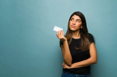 Daha iyi hissetmek için vitamin alan düşünceli bir kadın. Latin kadın bir hastalığı önlemek için ilaç almayı düşünüyor.