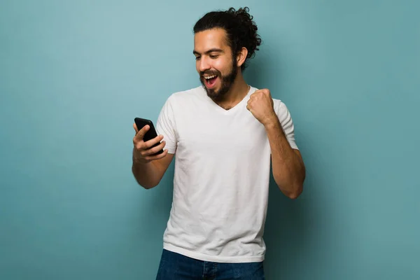 兴奋的拉丁男人阅读社交媒体 并在收到短信的好消息后庆祝 — 图库照片