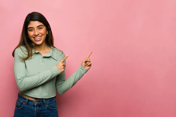 Houkutteleva Latino Nainen Osoittaa Sormella Kopioida Tilaa Edessä Vaaleanpunainen Tausta — kuvapankkivalokuva