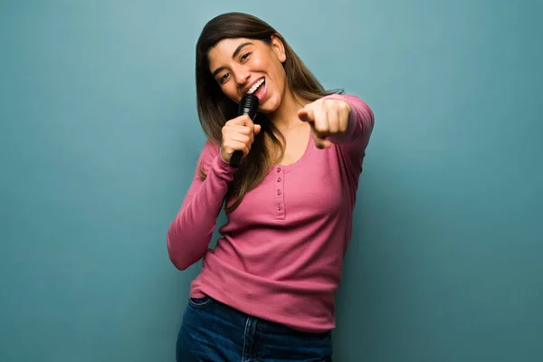 Pelaan Karaokea Hauska Latino Nainen Laulaa Mikrofonilla Osoittaa Eteenpäin Sinulle — kuvapankkivalokuva