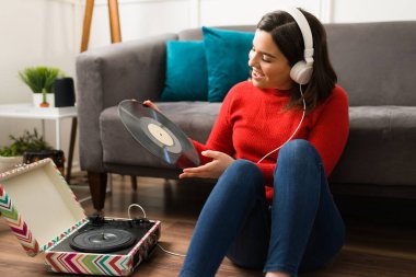 Müzik beni kurtardı. Sanatçı kadın oturma odasında oturmuş plak plaklarıyla müziğin tadını çıkarıyor.