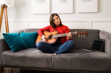 Bu şarkı senin için. Akustik gitar çalan ve dizüstü bilgisayarla kayıt yaparken aşk şarkısı söyleyen sanatçı bir kadın.