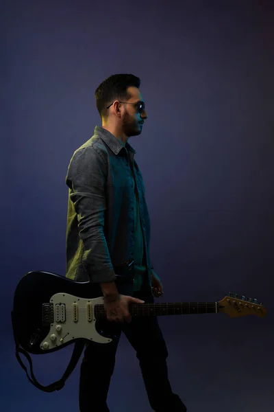 コンサートの前にロックやロールミュージックを練習しながらエレキギターを担ぐ男性ミュージシャンの側面図 — ストック写真