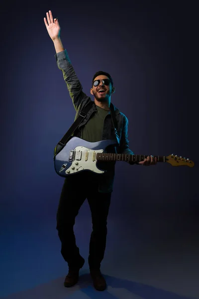 エレキギターを弾きながら腕を上げて観客を元気づける陽気な男性歌手やギタリスト — ストック写真
