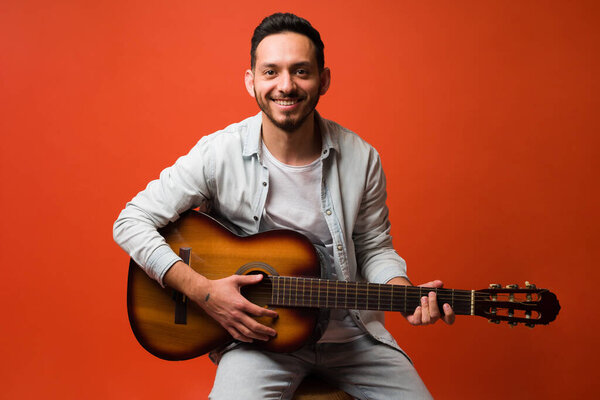 Portrait of a talented young male musician playing the acoustic guitar and singing a love song 