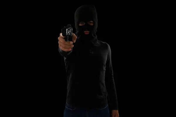 在枪口下被抢带着黑色巴拉克拉瓦的危险贼一边拿枪指着受害者一边偷钱 — 图库照片