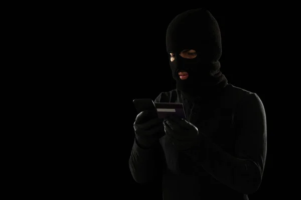 盗まれたクレジットカードを使用して熟練した覆面犯罪者は スマートフォンでオンラインで物事を購入する — ストック写真