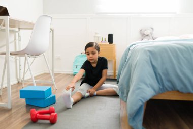 Egzersizleri ısıt. Sağlıklı yaşam tarzı olan aktif ilkokul kızı yatak odasında çalışıyor. 