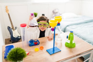 Neşeli çocuk odasında bilim deneyleri yapıyor ve büyüyünce bilim adamı olmak için kimya öğreniyor.