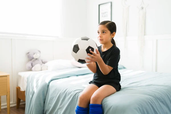 침대에 앉아서 축구공을 연습을 준비를 스러운 어린아이 — 스톡 사진