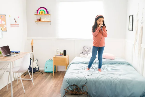 Utalentowana Dziewczynka Stojąca Łóżku Śpiewająca Mikrofonem Myśląc Byciu Sławną Piosenkarką — Zdjęcie stockowe