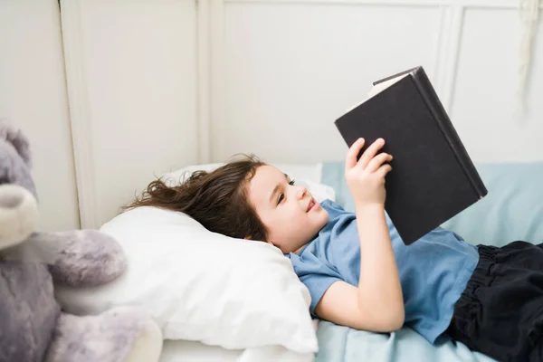 Vista Lateral Menino Adorável Lendo Divertido Livro Infantil Seu Quarto — Fotografia de Stock