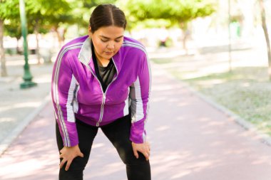 Açık havada yapılan güçlü bir kardiyo çalışmasından sonra yorgun düşmüş şişman bir kadın. İri yarı kadın koştuktan sonra yorgun hissediyor. 