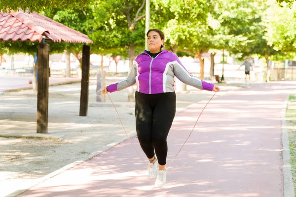 活跃的恐慌女人在公园里跳绳 体重超标的女人燃烧卡路里来减肥 — 图库照片